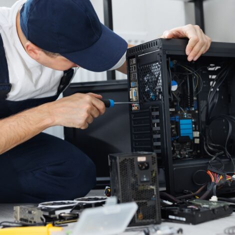 Closeup computer technician holding a screwdriver and repairing a pc.