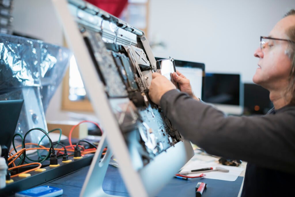 Your Go-To Apple Mac Repair Expert In Clacton Near You 1 Computer Repair Shop,USA,Computer Repair Shop. A man with a computer monitor, taking it apart to mend it.