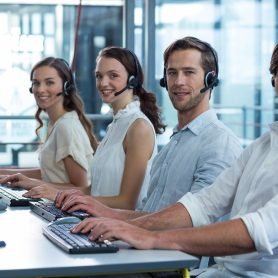 Portrait of business executives with headsets using computer in office